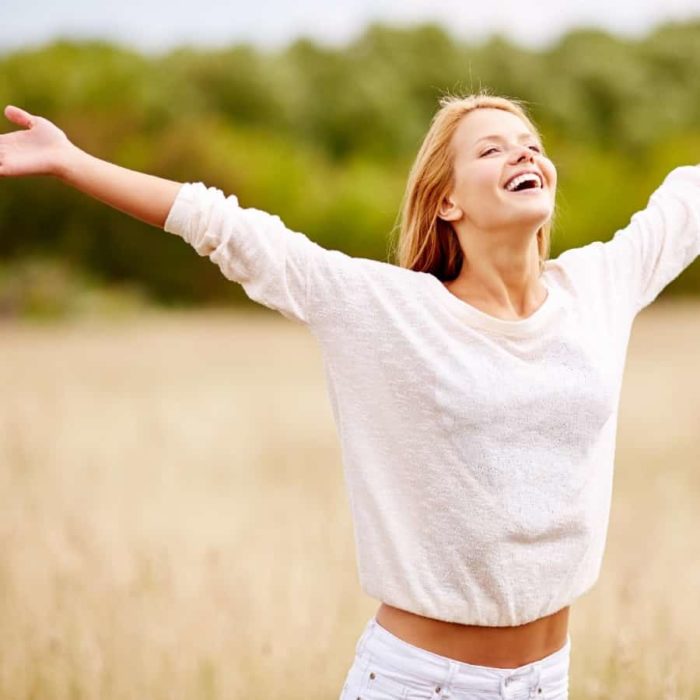 Happy woman in a field with big smile on her face.